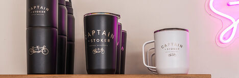 Customized bottles and drinkware sitting on top of a shelf in a coffee shop